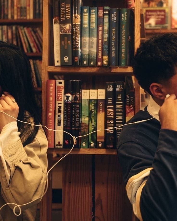 Couples listening to music on opposite sides of a bookshelf — In Relation Resource